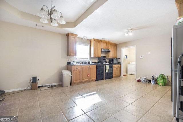 kitchen with light tile patterned floors, black range with electric stovetop, a tray ceiling, washer / dryer, and a chandelier