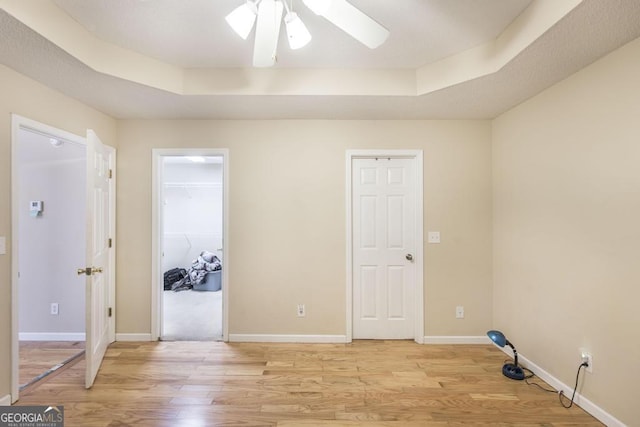 empty room featuring a tray ceiling, light hardwood / wood-style flooring, and ceiling fan