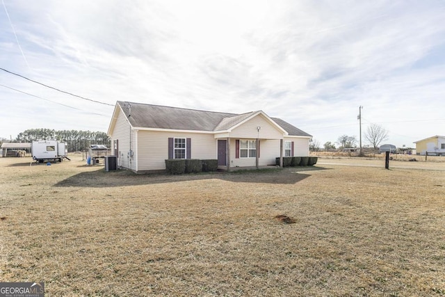 view of front of home with central AC and a front yard