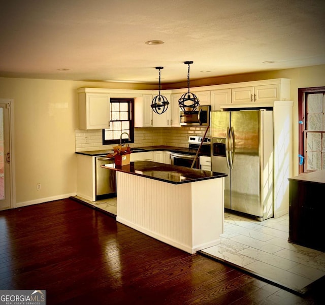 kitchen with white cabinetry, decorative light fixtures, stainless steel appliances, and a kitchen island