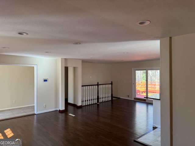 unfurnished room with a textured ceiling and dark hardwood / wood-style flooring