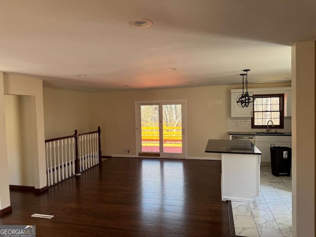 kitchen with sink, dishwasher, white cabinets, pendant lighting, and backsplash