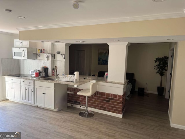 kitchen with white cabinetry, sink, light stone counters, and a breakfast bar