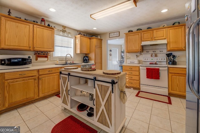 kitchen with sink, a textured ceiling, light tile patterned floors, white appliances, and decorative backsplash