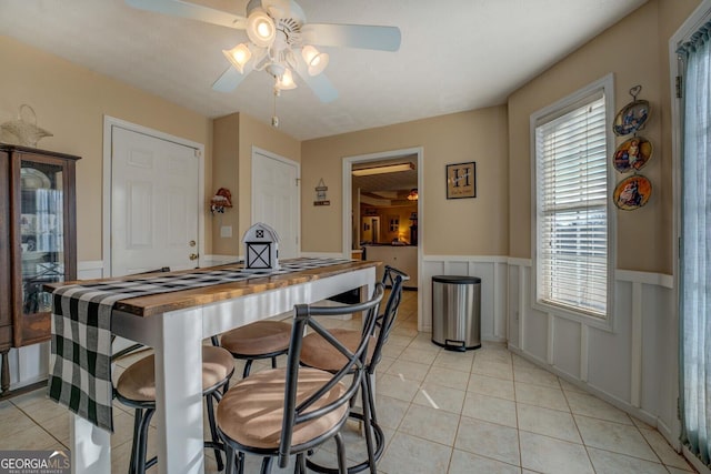 kitchen featuring ceiling fan, wooden counters, a breakfast bar area, and light tile patterned floors