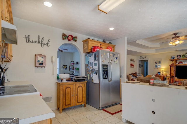 kitchen with a raised ceiling, light tile patterned floors, ceiling fan, and stainless steel fridge with ice dispenser