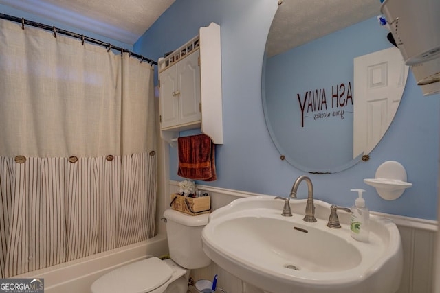 full bathroom featuring shower / bath combination with curtain, sink, toilet, and a textured ceiling