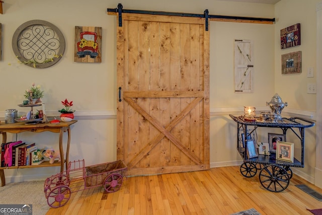 interior space with a barn door and hardwood / wood-style floors