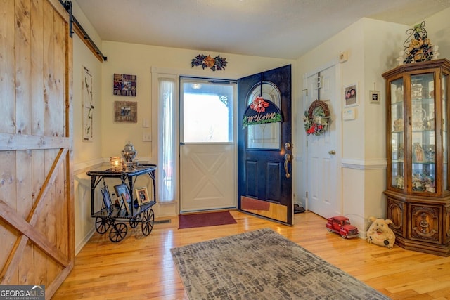 entryway with a barn door and light hardwood / wood-style flooring