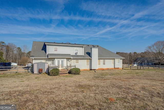 back of property with a deck, a shed, and a lawn