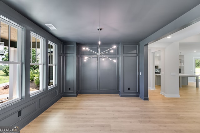 662 Lake Circle Rd, Buchanan, GA 30113 - unfurnished dining area featuring a chandelier, light wood-style flooring, a decorative wall, and baseboards