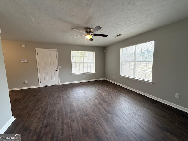 spare room featuring dark wood-type flooring, ceiling fan, and a textured ceiling