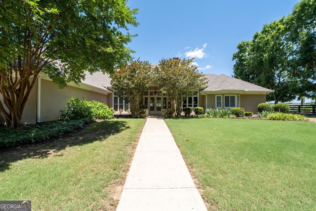 view of front of property with fence, a front lawn, and stucco siding