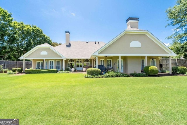 rear view of property with covered porch and a lawn