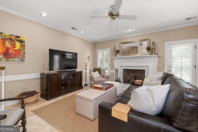 carpeted living room with ceiling fan, ornamental molding, and a brick fireplace