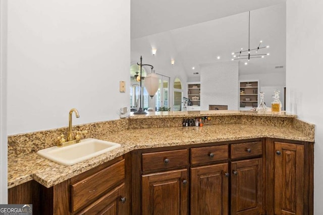 kitchen with light stone countertops, sink, and kitchen peninsula