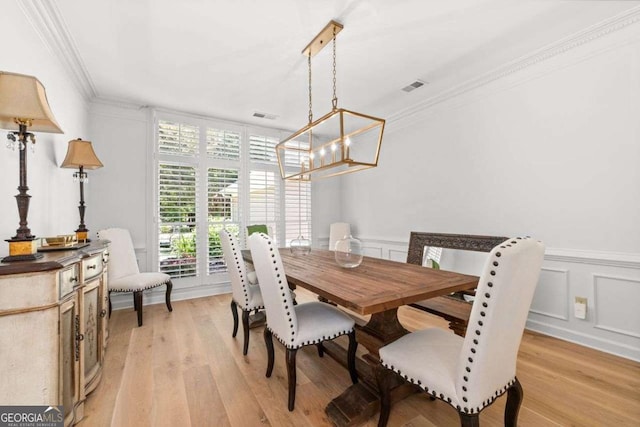 dining room featuring a notable chandelier, crown molding, and light wood-type flooring