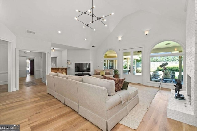 living room featuring high vaulted ceiling, light hardwood / wood-style floors, and french doors