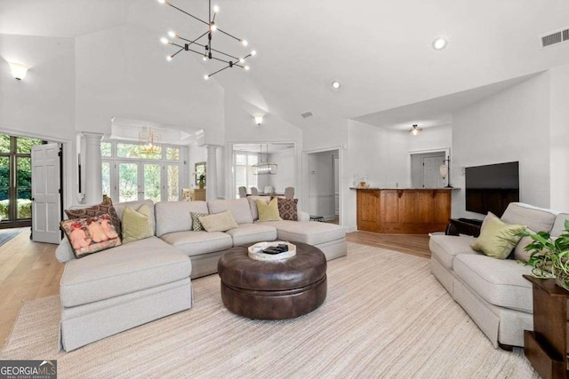 living room with light wood-type flooring, a wealth of natural light, and ornate columns