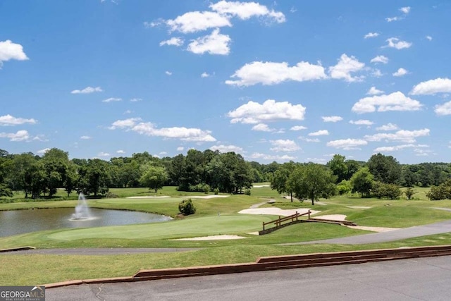 surrounding community with a water view and a lawn