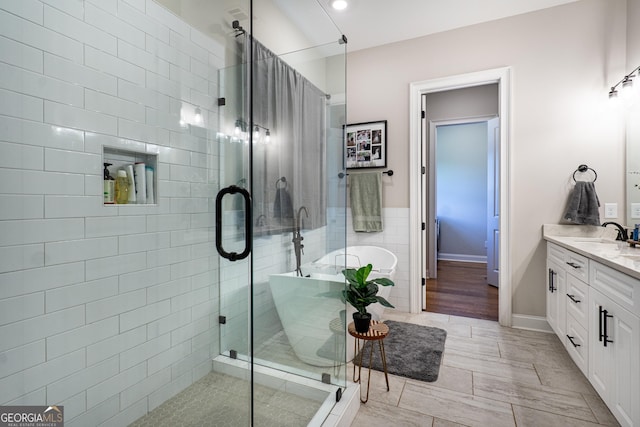 bathroom featuring a stall shower, a soaking tub, and vanity