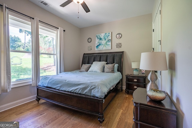 bedroom with baseboards, visible vents, multiple windows, and wood finished floors