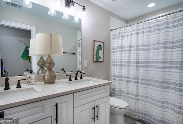 bathroom with toilet, double vanity, a sink, and visible vents