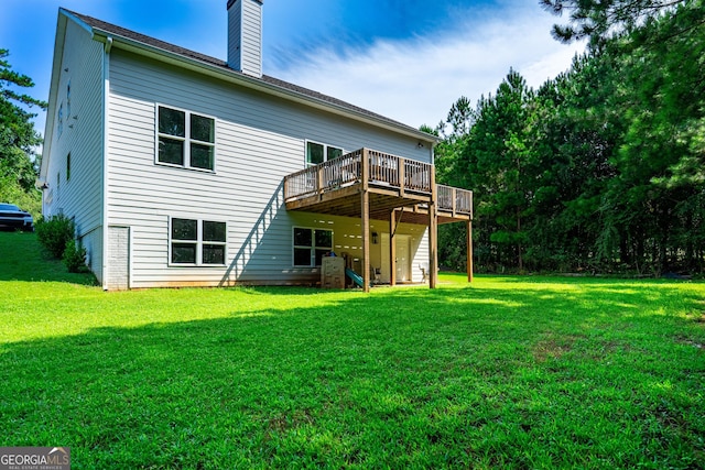 rear view of house with a deck, a yard, and a chimney