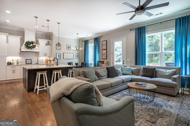 living area featuring visible vents, dark wood-style floors, ornamental molding, ceiling fan with notable chandelier, and recessed lighting