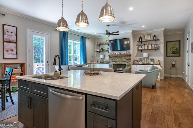 kitchen featuring a kitchen island with sink, a sink, open floor plan, stainless steel dishwasher, and decorative light fixtures