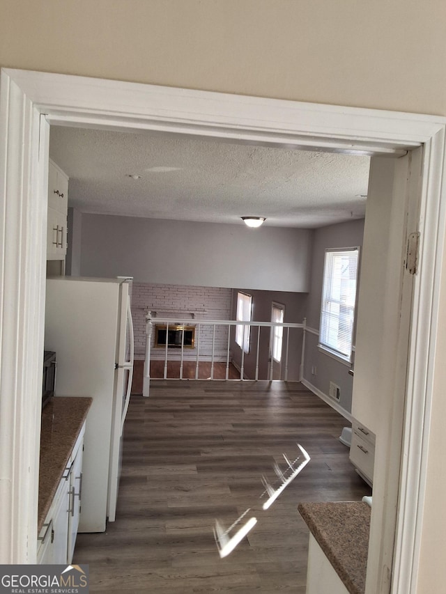 kitchen with dark hardwood / wood-style floors, a textured ceiling, white fridge, and white cabinets