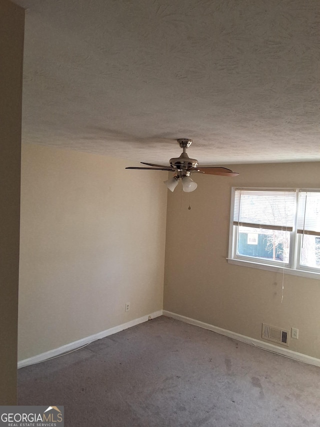 carpeted empty room with ceiling fan and a textured ceiling