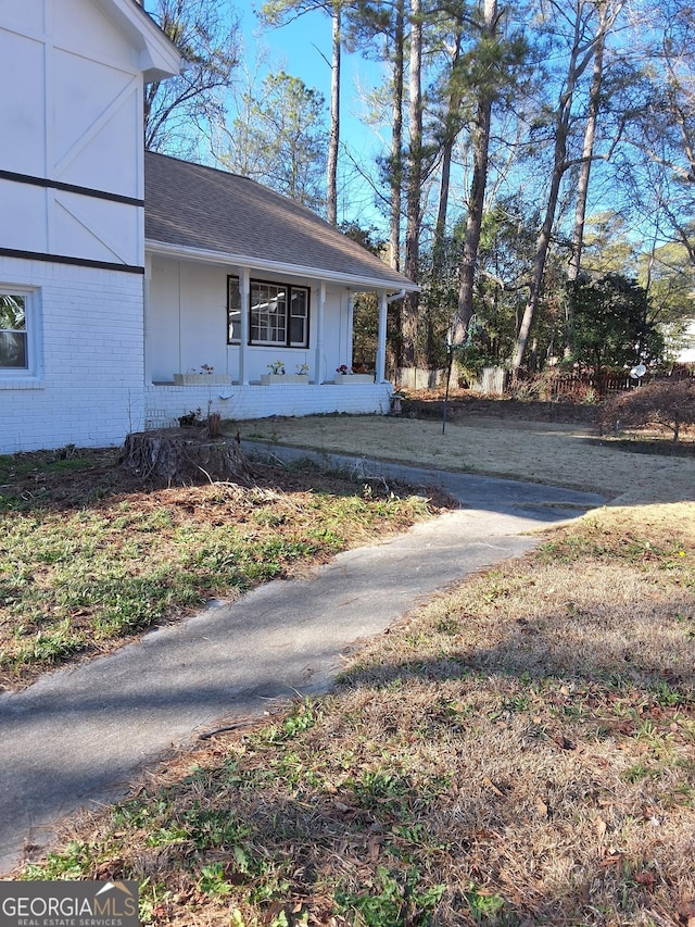 view of side of home with a yard and covered porch