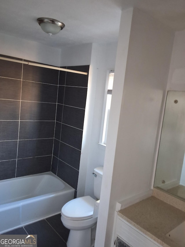 bathroom with tile patterned floors, toilet, and tiled shower / bath combo