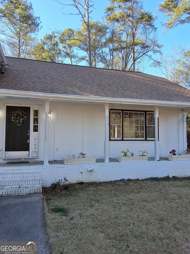 property entrance with a porch and a lawn