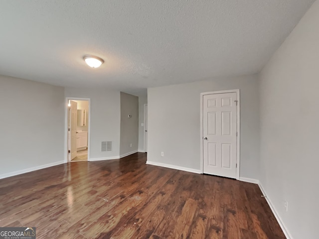 spare room with a textured ceiling and dark hardwood / wood-style flooring