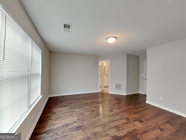 spare room with dark hardwood / wood-style flooring and a textured ceiling