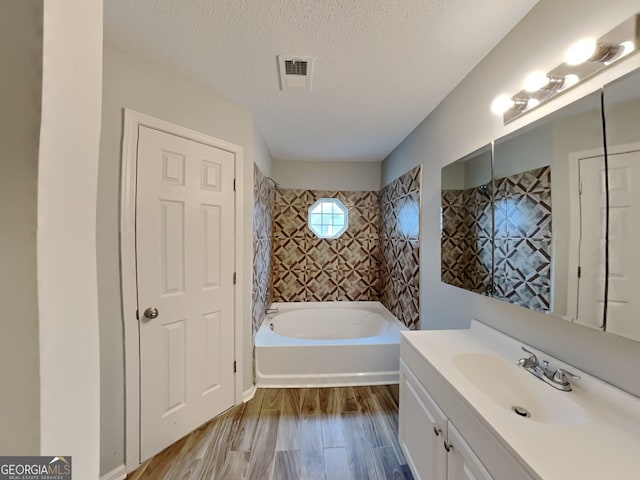 bathroom featuring tiled shower / bath, vanity, hardwood / wood-style floors, and a textured ceiling