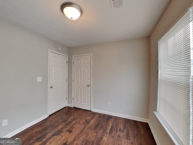 spare room featuring dark hardwood / wood-style floors and a textured ceiling