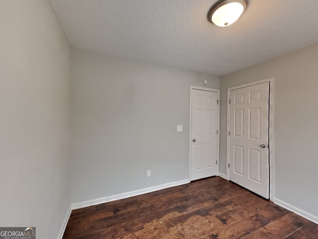 spare room featuring dark wood-type flooring and a textured ceiling