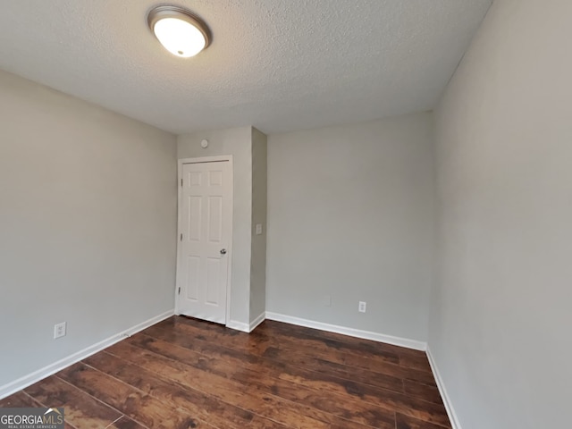 spare room with dark wood-type flooring and a textured ceiling