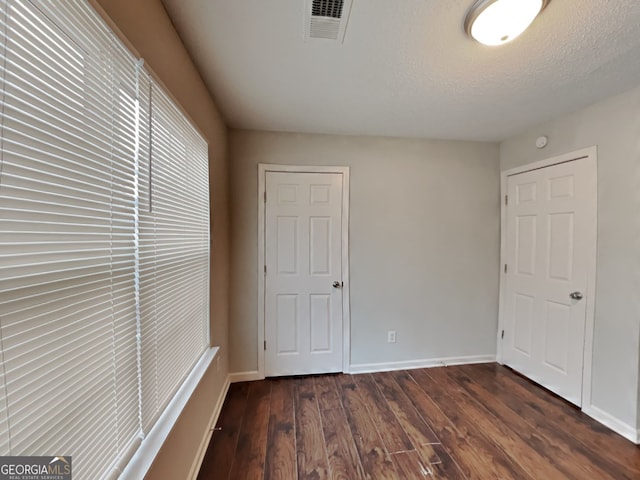 unfurnished bedroom with dark wood-type flooring and a textured ceiling