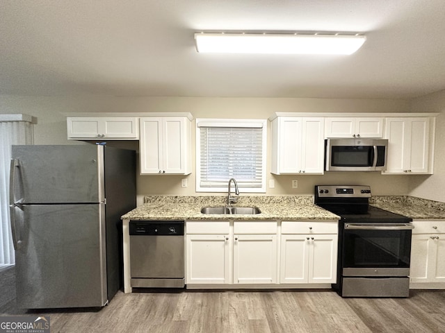 kitchen with white cabinetry, sink, stainless steel appliances, and light wood-type flooring