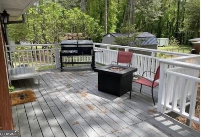 wooden terrace featuring a grill and an outdoor fire pit