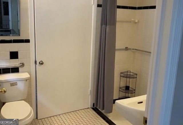 bathroom with tile walls, tile patterned floors, a shower with shower curtain, and toilet