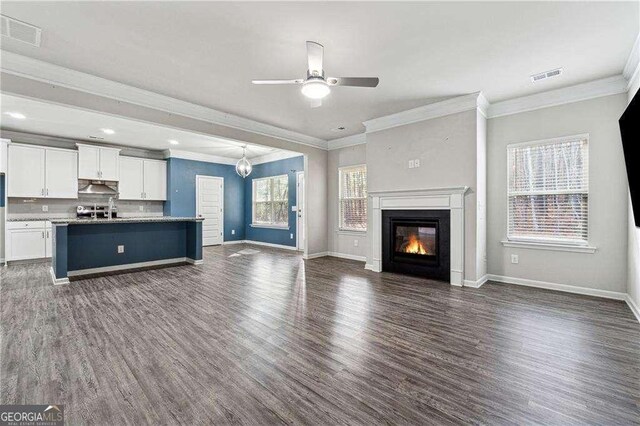 unfurnished living room with ceiling fan, a healthy amount of sunlight, and dark hardwood / wood-style flooring