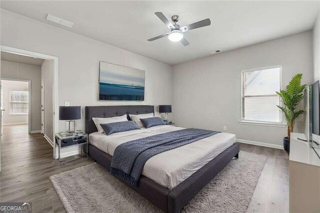 bedroom featuring ceiling fan, dark hardwood / wood-style floors, and multiple windows