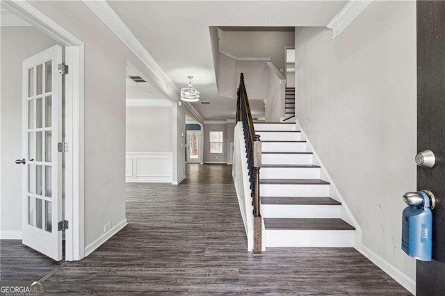 stairs featuring french doors, ornamental molding, and wood-type flooring