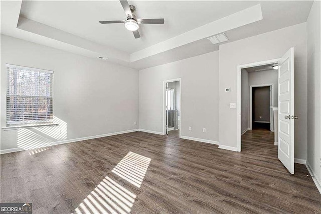 unfurnished room featuring dark hardwood / wood-style floors, ceiling fan, and a tray ceiling