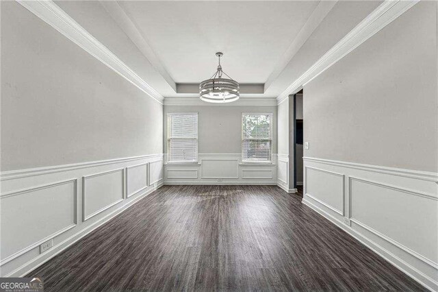 interior space with dark hardwood / wood-style floors, a chandelier, and a tray ceiling